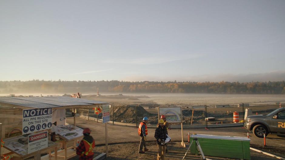 Construction workers mill around the site.