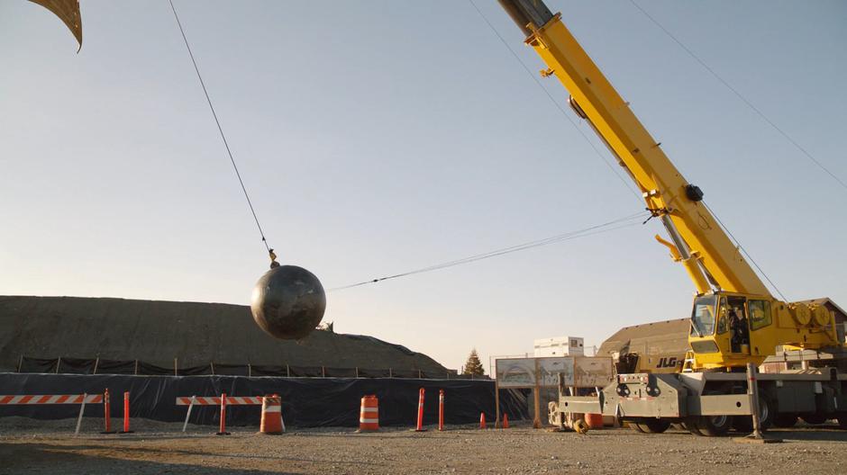 Mr. T sits behind the controls of a wrecking ball preparing to demolish the main gate.