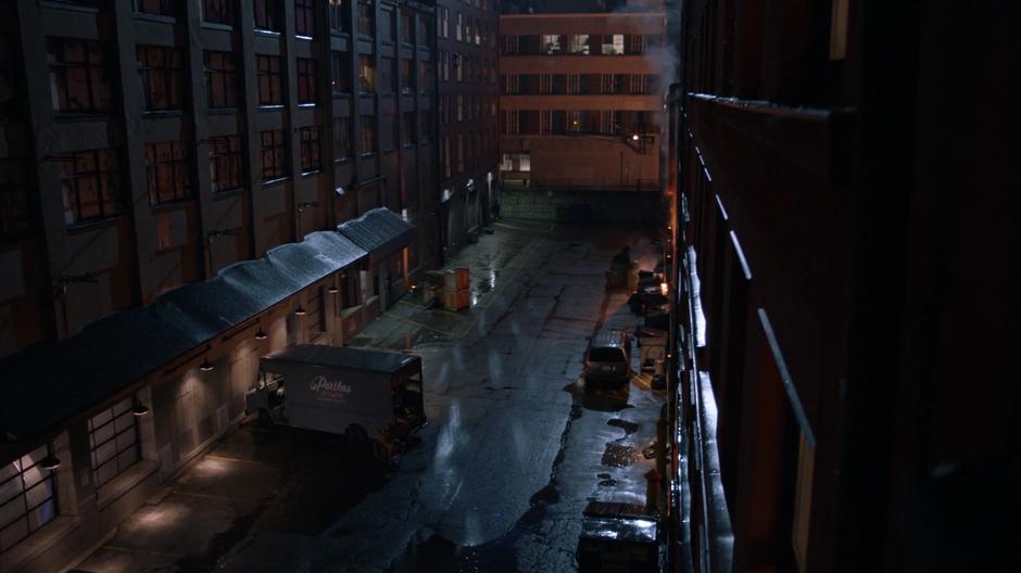 A man loads his truck in the alley at night.