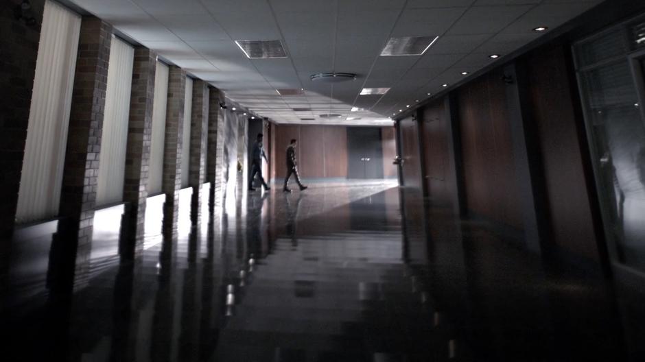 Two teenagers exit the elevator down the hallway.