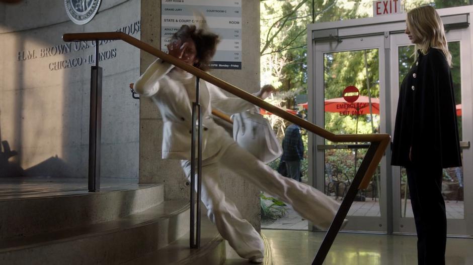 The mysterious woman watches as Cate Monroe falls down onto the stairs.