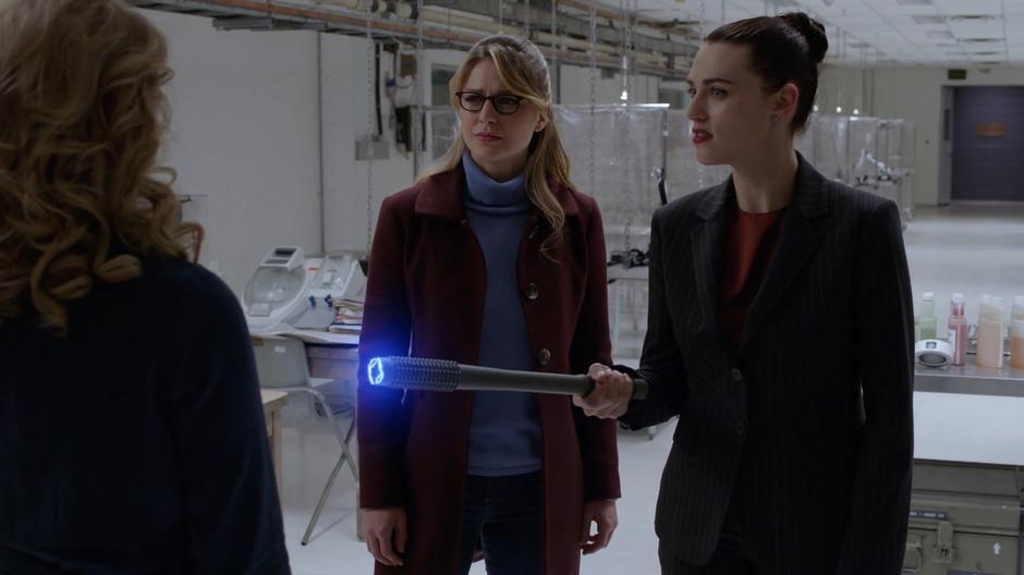 Lena holds out the electric baton while interrogating Eve with Kara.