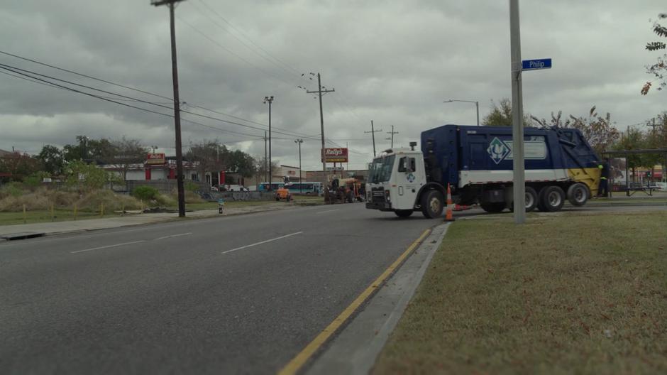 A garbage truck turns the corner near the motel.