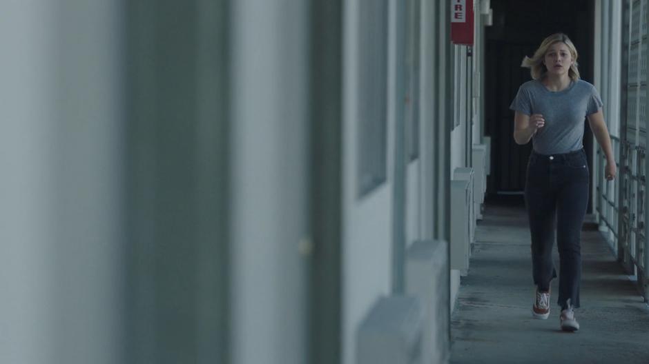 Tandy walks quickly down the upstairs courtyard hallway.