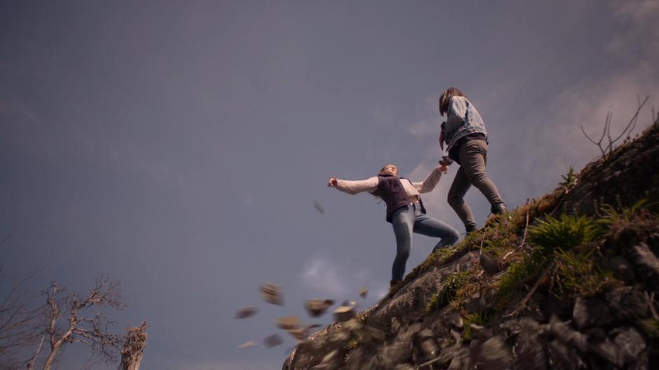 Young Kara and Alex slip off the side of a cliff when Kara claps too loud.