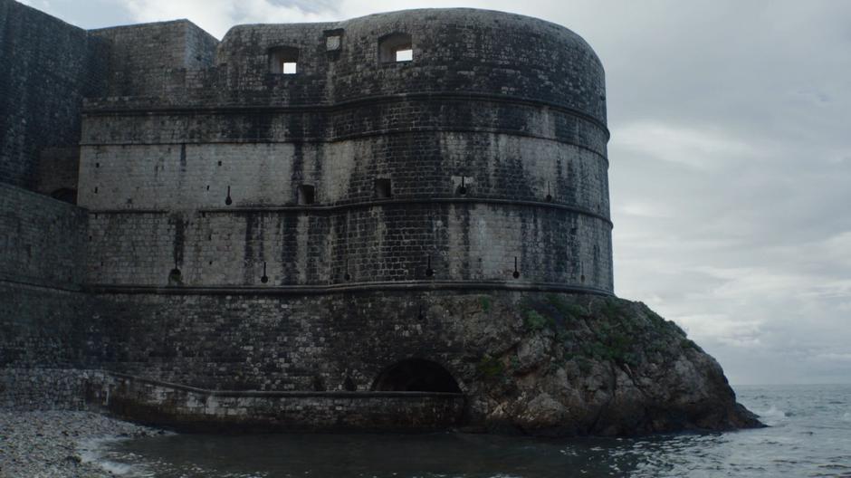 Jon is escorted out from under the city's walls towards the small harbour.