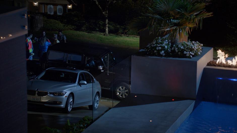 A car is parked in the street blocking Blaine's driveway as the party from next door spills over.