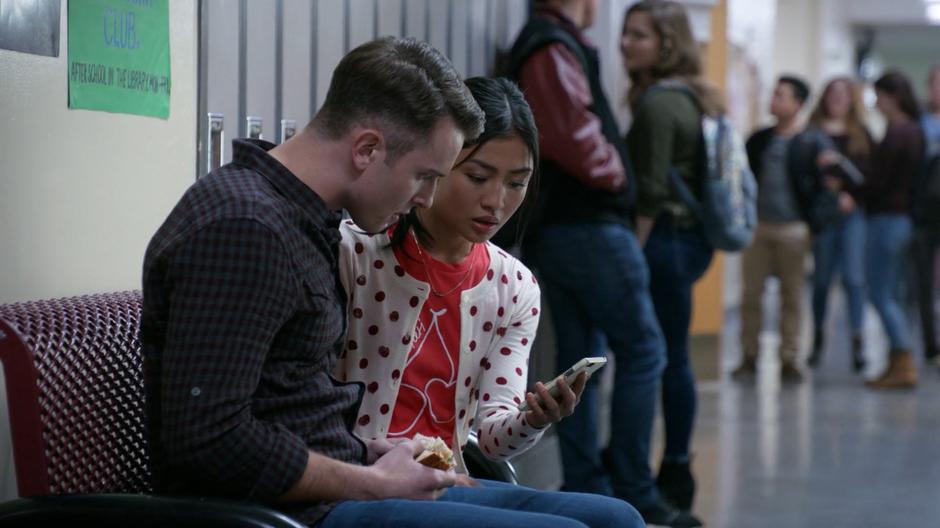 Jaime and Amy sit next to one another in the hall and watch the video apparently from Harris.