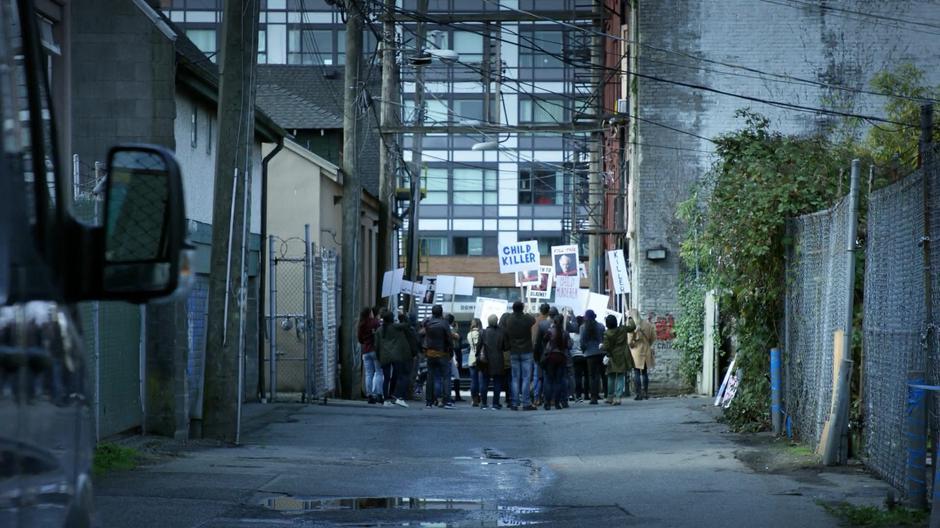 Protestors congregate down the alley yelling outside the door of the Scratching Post.