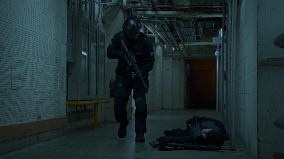 Peters looks down at the body of another mercenary while searching the basement for the intruders.