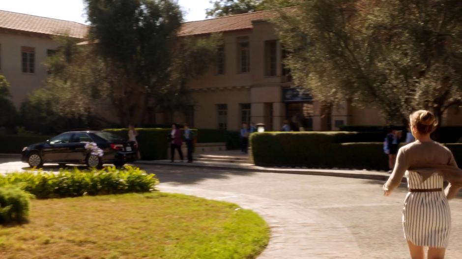 Kara runs towards the pickup area outside the school.