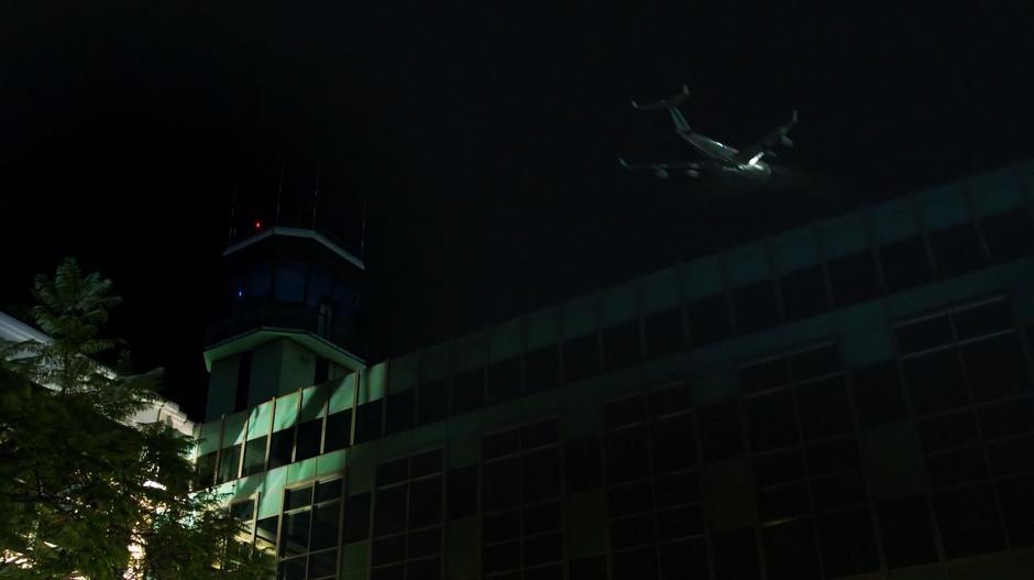 A plane flies overhead past the terminal.