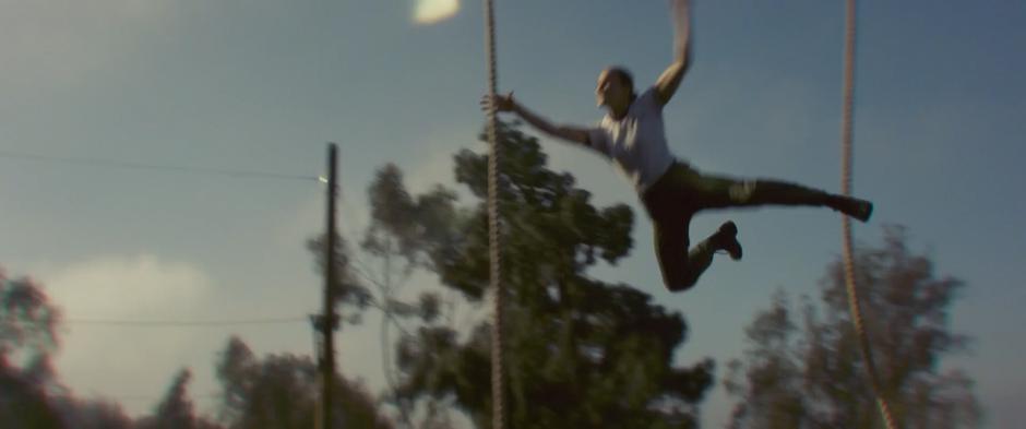 Carol leaps from a rope and tries to grab the next one over.