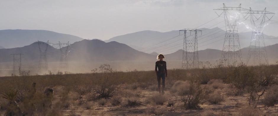 Carol strides towards Yon-Rogg's crash site as the last of the power surge flows through the high-tension lines behind her.