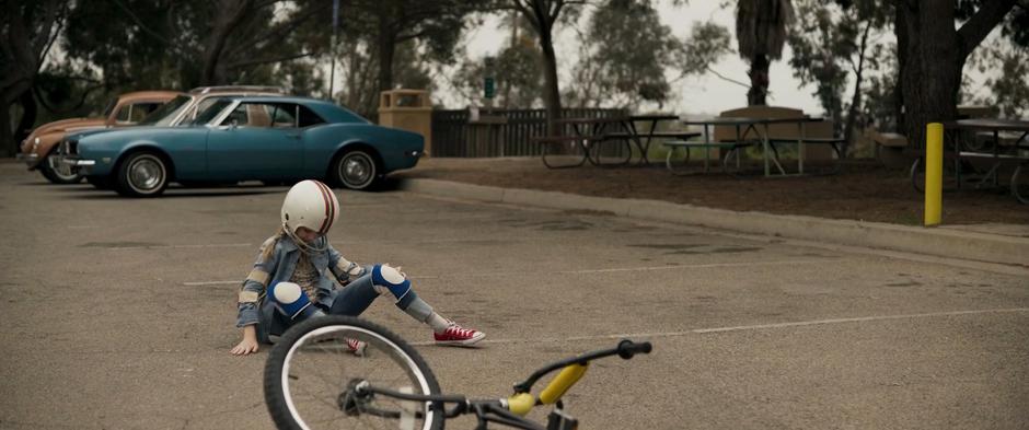 Young Carol climbs to her feet after crashing her bike.