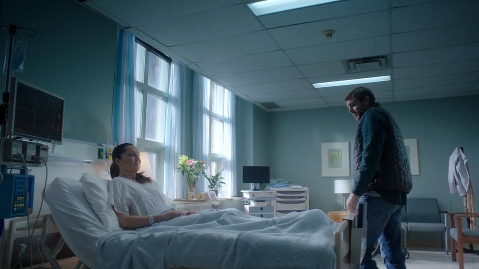 Ben approaches Elaine's hospital bed after getting news of her spreading paralysis.