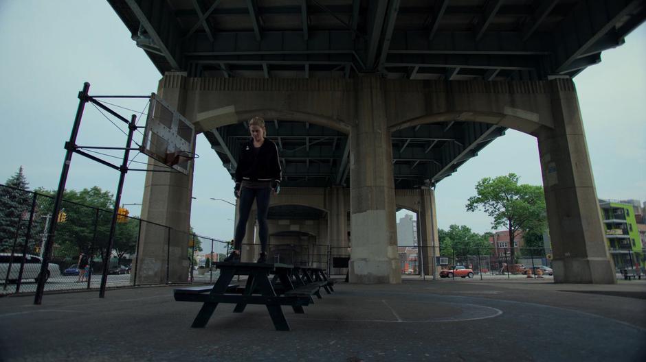 Trish stands on the edge of a picnic table and prepares to hop down.