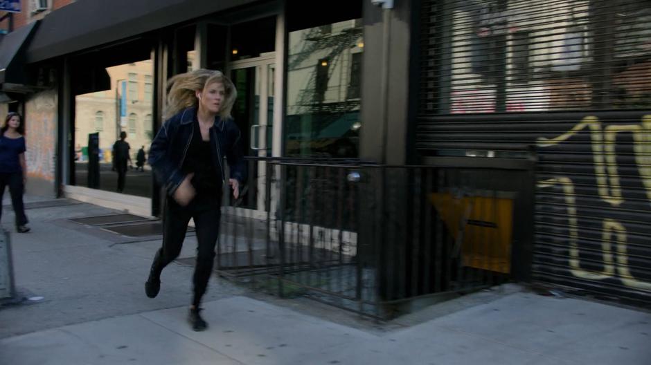 Trish starts running back down the street after hearing something on her police scanner.
