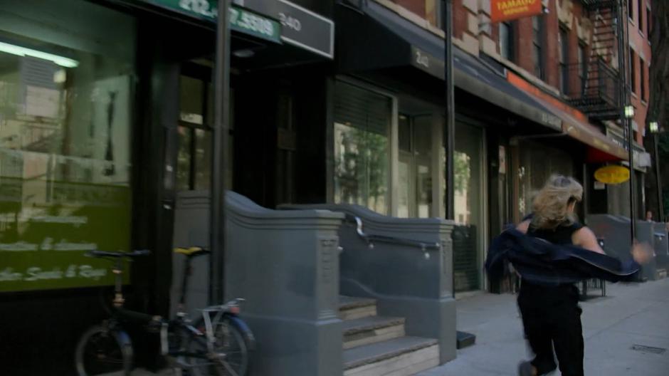 Trish races off down the sidewalk towards the crime in progress.