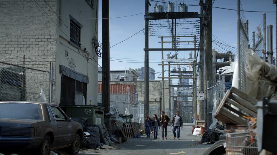 Annie, Pippi, Oliver, and Baron walk down the alley towards the wall of the city.