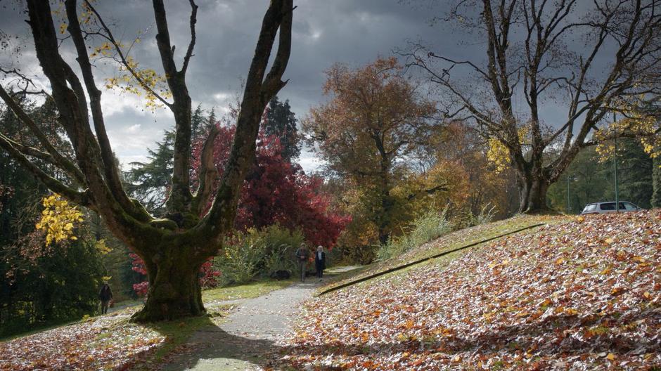 Martin Roberts and Liv walk down the path talking past the leaf-covered ground.