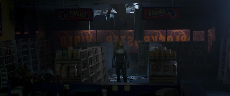 Vers stands in the middle of the video store next to a pile of debris from when she crashed through the ceiling.