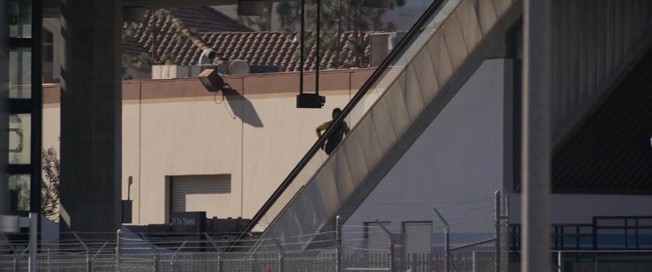 The Skrull runs up the escalator leading to the station.