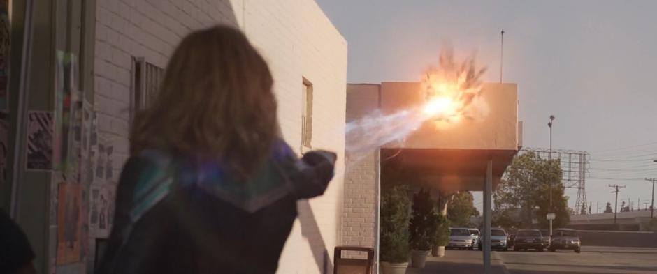 Vers fires a photon blast at the Skrull but hits the edge of the building instead.