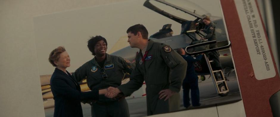 A photograph in the file shows Dr. Lawson shaking the hand of a pilot while standing with Maria while behind them Carol prepares her fighter with a member of the ground crew.