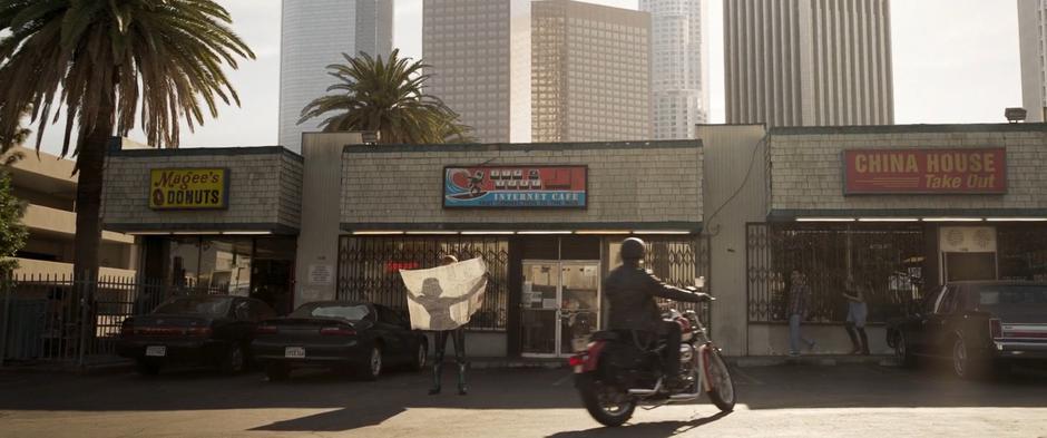 Vers is reading a map in front of the cafe when a man pulls up on a motorcycle.