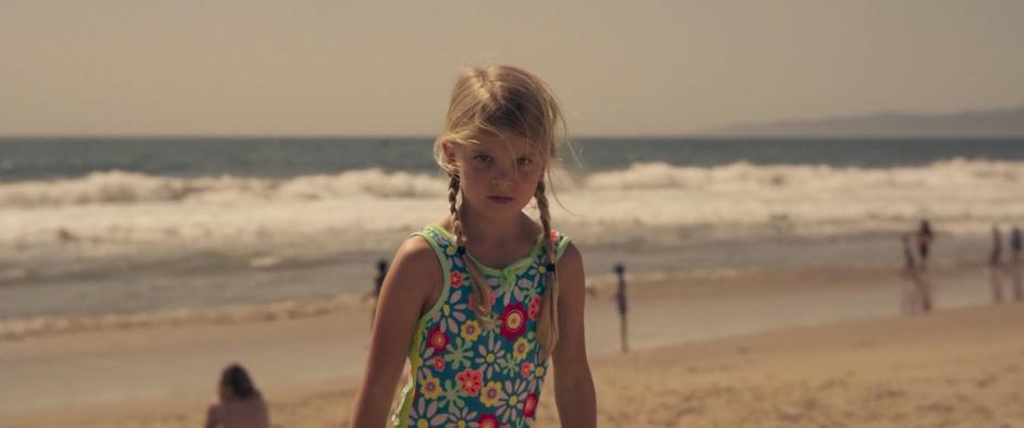 Young Carol stands up on the beach with a determined look on her face.