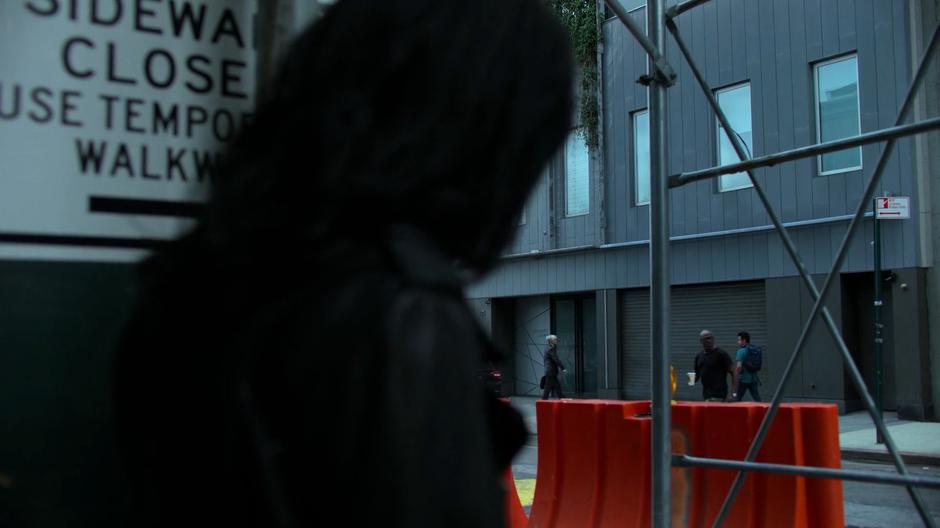 Jessica watches from across the street as someone approaches the door of the gallery.