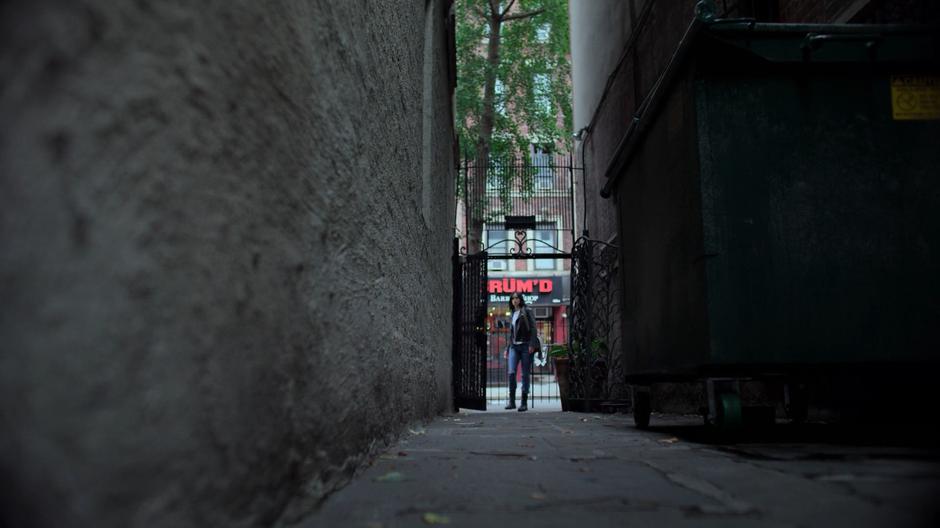 Jessica enters the alley where the drop was supposed to be hidden.