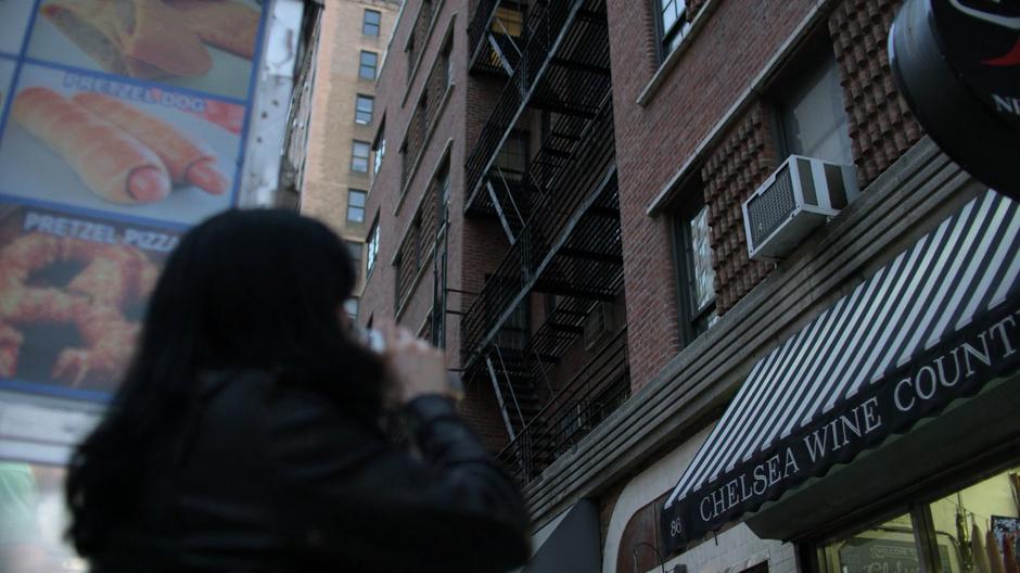 Jessica stands on the street looking up at the building.