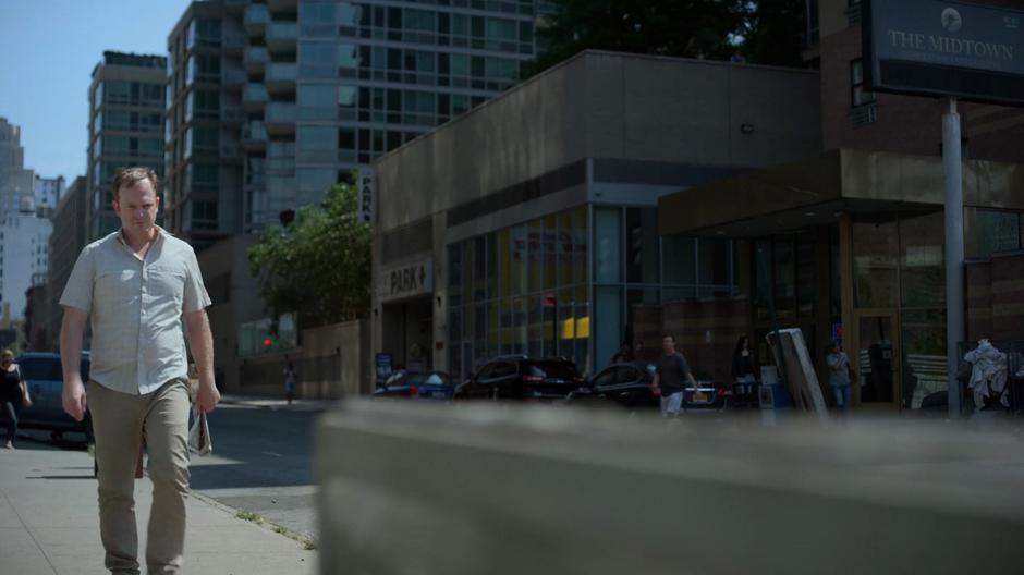 Gregory Sallinger walks down the street towards a bench while Jessica watches him from across the street.