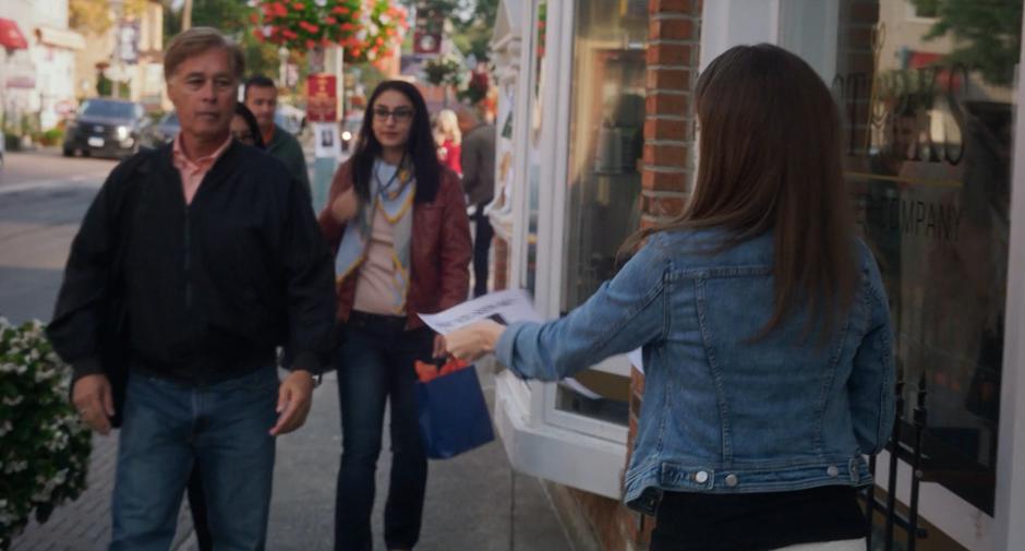 Stephanie hands out missing person fliers to people walking down the street.