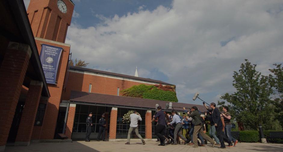 A mob of reporters follow Sean as he is led to the courthouse.