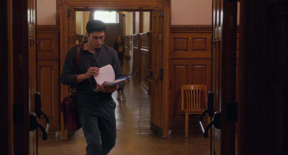 Sean walks down the hallway looking at some papers.