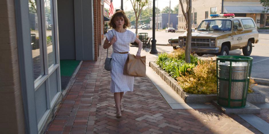 Nancy walks down the sidewalk in front of the store on her way to work.