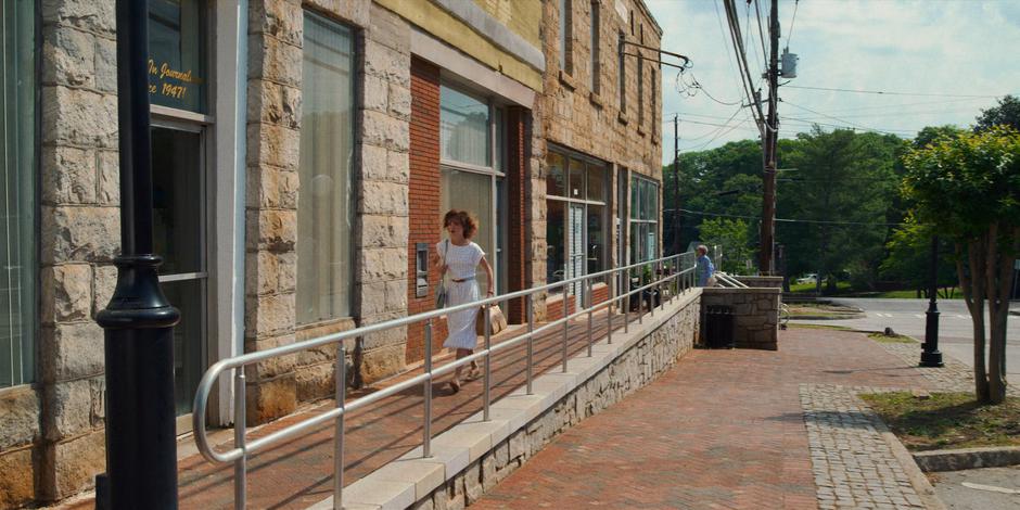 Nancy rushes down the sidewalk to the door of the newspaper with a bag full of coffee.