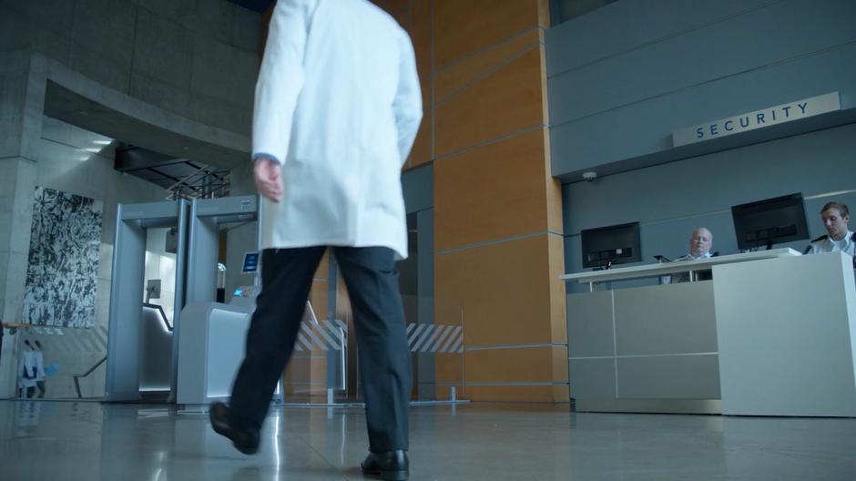 Dr. Saxon walks through the lobby towards the security checkpoint.