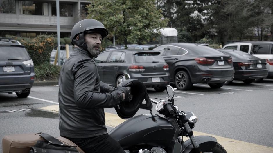 A man on a motorcycle holds out a helmet for Candy.