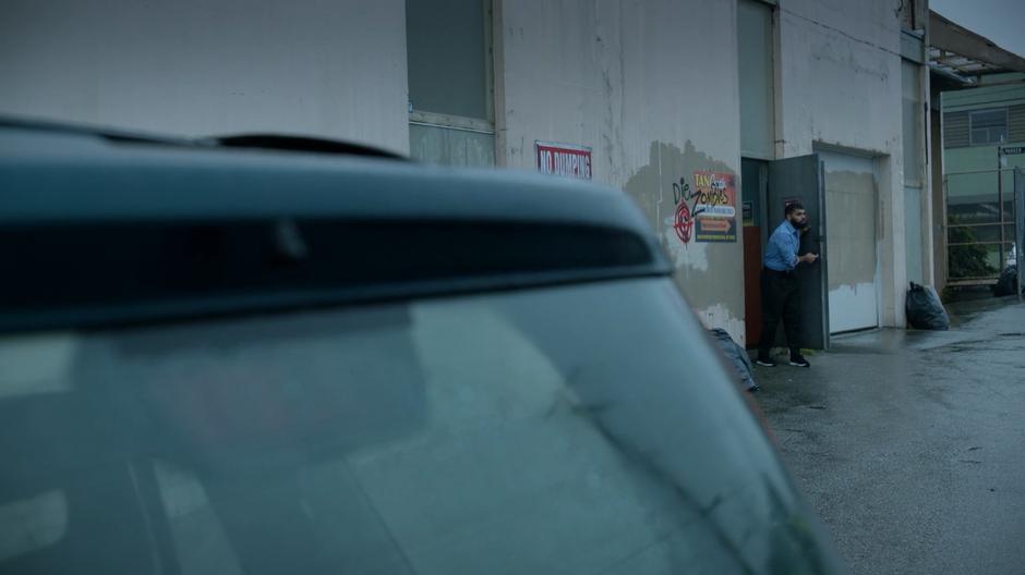 The tanning salon employee checks that the alley is clear.