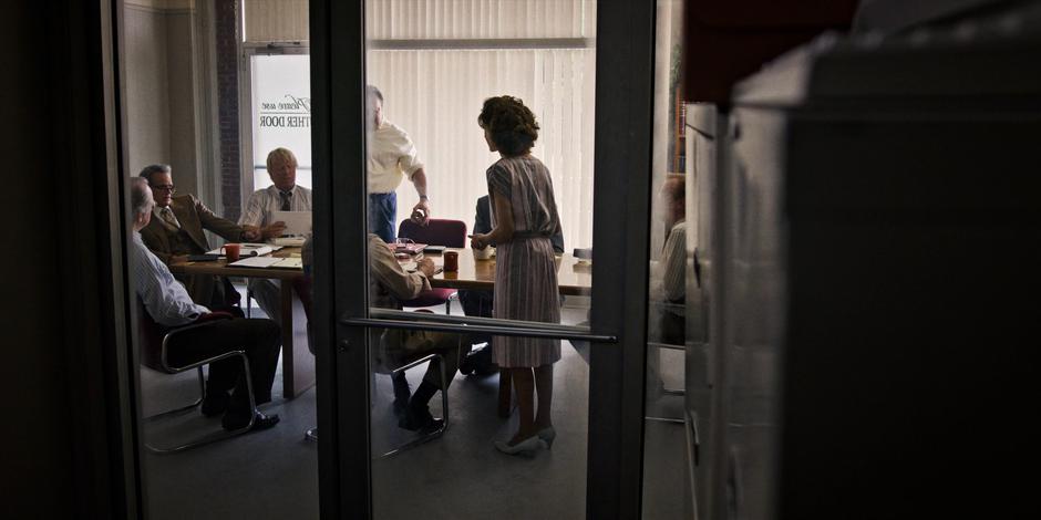 Nancy pitches her crazy rat story to Tom Holloway, Bruce, and the other journalists.