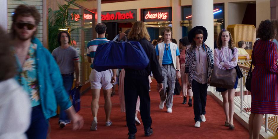 The suspicious guy carrying a duffel bag walks through the crowded mall.