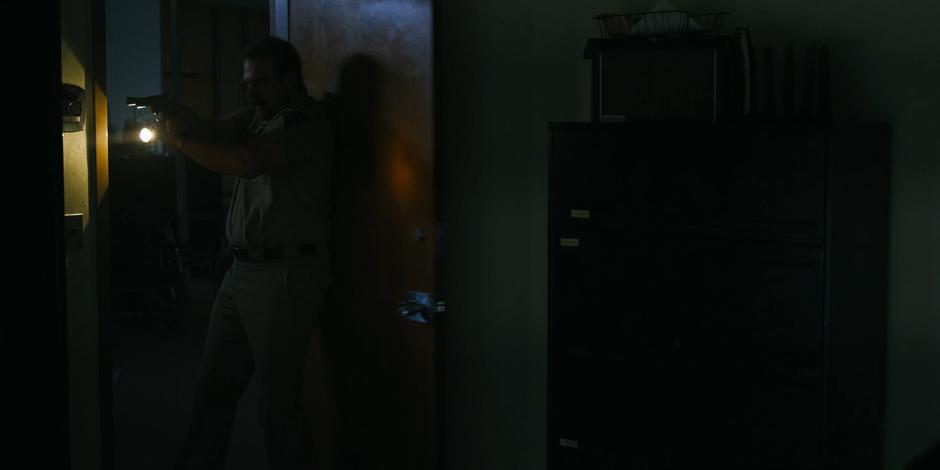 Hopper searches one of the offices with his gun and flashlight after hearing a sound.