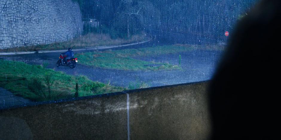 Joyce sees a man riding off on a motorcycle in the rain.