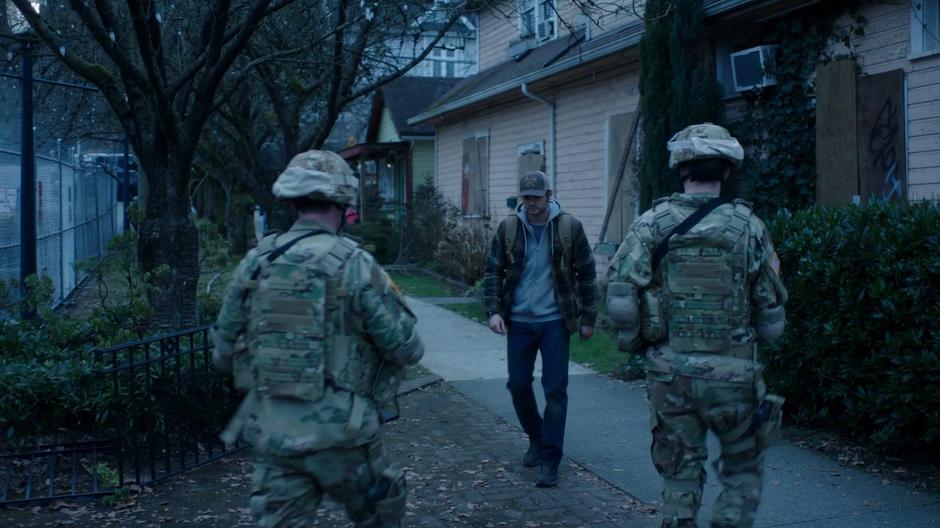 Ben keeps his head down as he walks past two soldiers.