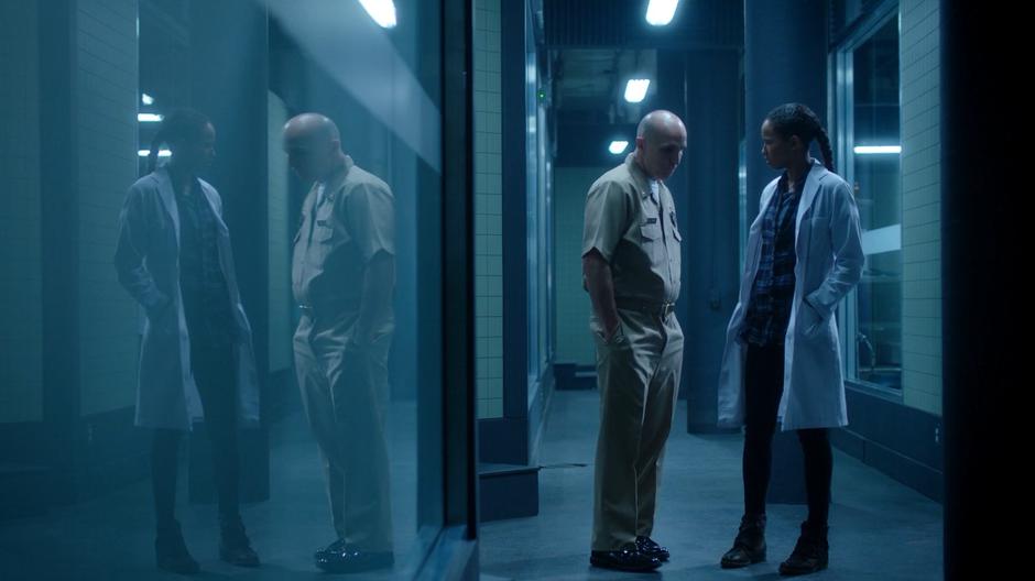 Commander Kyle stops to talk with Maddie in the hallway while she is working in a lab coat.