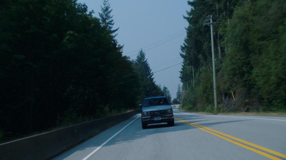 Maddie and Ben drive down a road through the trees.